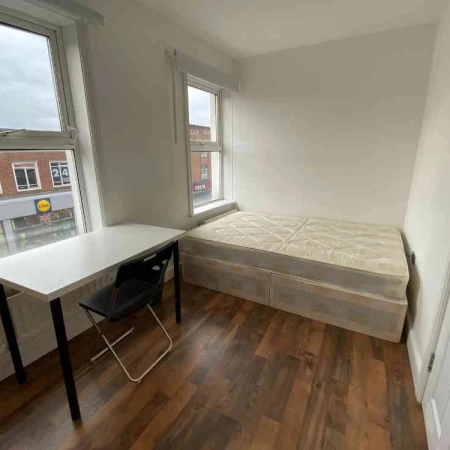 A room with a double bed, 2 large windows, a table and a chair.
