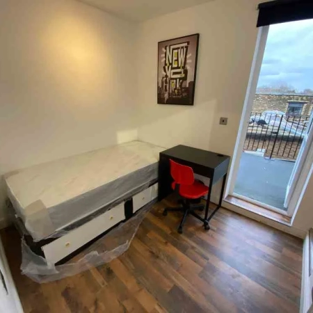 A room with a single bed, a table, a chair, a wall frame and a door leading to the terrace.