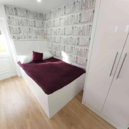 In this large Streatham room, a bed adorned with red bedding and pillows takes centre stage. The wardrobe is conveniently located at the foot of the bed.
