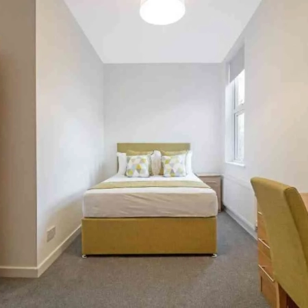In this furnished bedroom in Kennington Park, there's a bed with pillows at the head, and a window on the side.