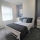 This double bedroom for rent in Central London includes a bed with bedding and pillows, cabinets on both sides of the bed, and a window on the left side.