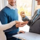 The woman is handing a key to a couple in the 'Choosing the Right Property Manager' blog.