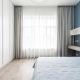A bed and a large window with a curtain in the House Share in London blog.