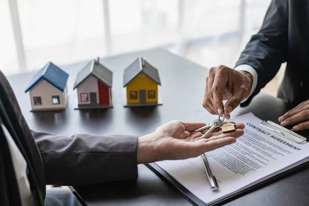 A hand passing a key to another hand against the backdrop of three display houses in the 'Landlord's Success with Rent-Guaranteed' blog