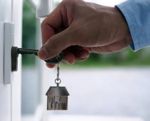 A hand, holding a key with a house keychain, is inserting it into a door in the 'London's Guaranteed Rent Growth' blog.