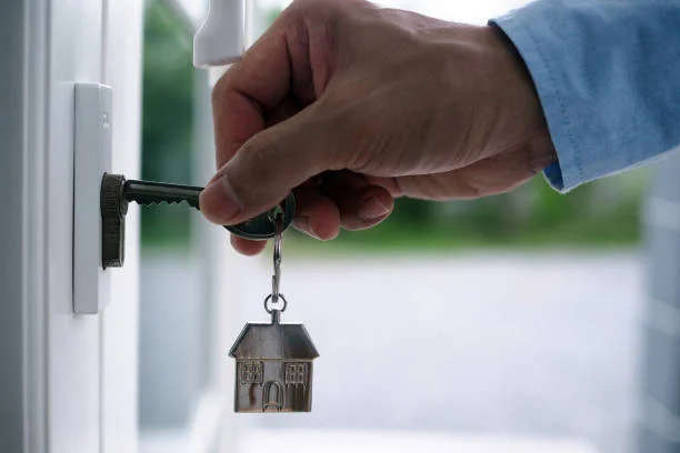 A hand, holding a key with a house keychain, is inserting it into a door in the 'London's Guaranteed Rent Growth' blog.