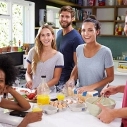 A group of men and women in the kitchen preparing snacks in this blog titled: Opting for flatshare.