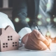 Hand writing with a display house and a white hard hat in the Protecting Your London Rental Income blog.