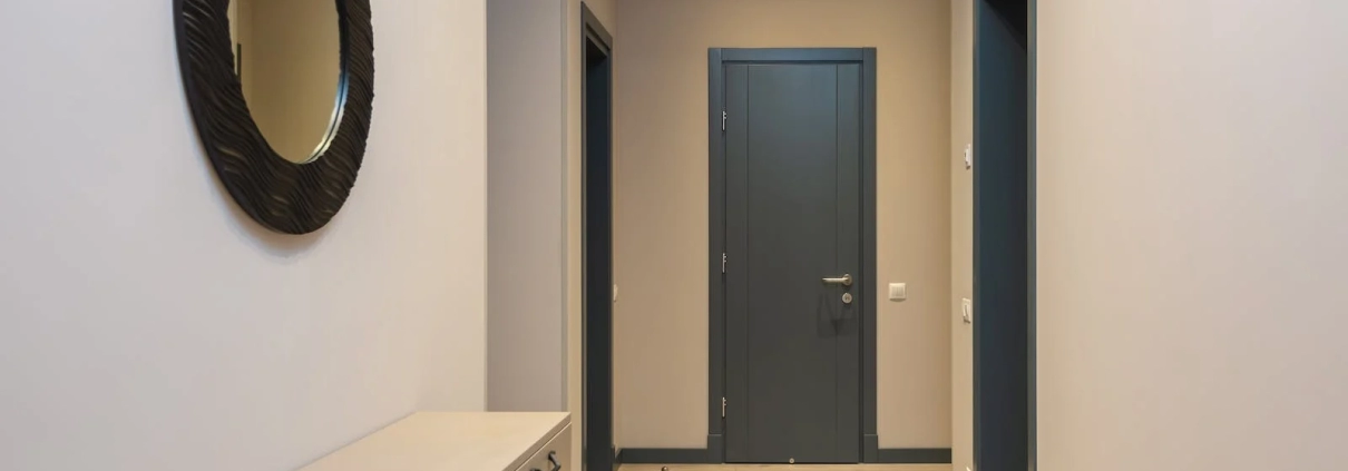 This hallway has cabinets and wall mirror on the left and doors on the end in this London Room Rental Market.