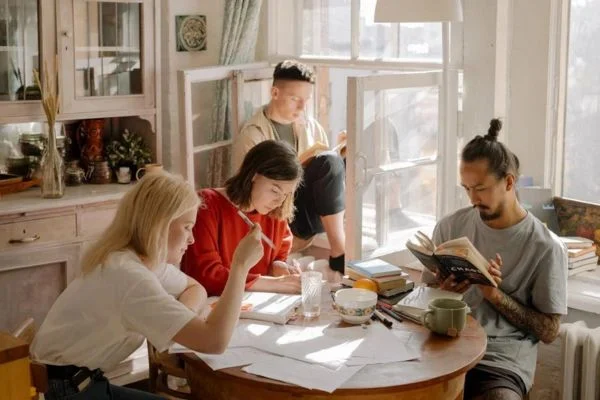 Students sitting on a table and studying in a bright room in the Guaranteed Rent Management blog.