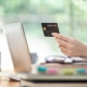 A lady's hand holding a credit card facing the laptop in the Guaranteed Rental Schemes in London blog.